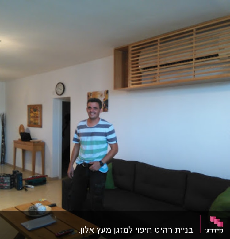 אדם עומד בסלון עם שולחן עץ קטן